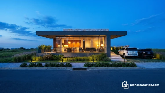 Fachada nocturna de los planos de casa moderna Viesca con grandes ventanales e iluminación cálida.