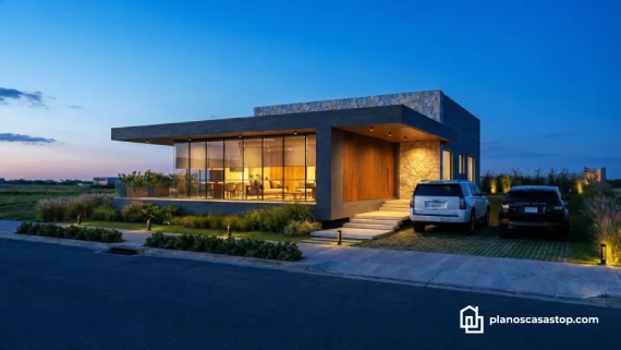 Fachada iluminada de planos de casa moderna Viesca con grandes ventanales, muros de piedra y acabados en madera al atardecer.