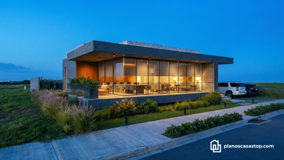 Fachada de cristal y concreto al atardecer inspirada en los planos de casa moderna Viesca con iluminación cálida.