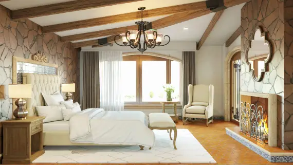 Recámara principal de lujo de los Planos de casa colonial manzano, con chimenea de piedra, techo de vigas y mobiliario elegante.