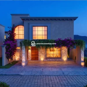 Fachada nocturna de los Planos de casa colonial Sauce con muros de piedra, pérgola con buganvilias y ventanas iluminadas.
