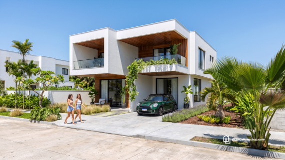 Fachada de planos de casa moderna arrayán con dos niveles, acabados en madera, vegetación tropical y auto verde estacionado.