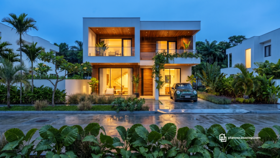 Fachada con madera y luces cálidas según los planos de casa moderna arrayán en un entorno tropical.